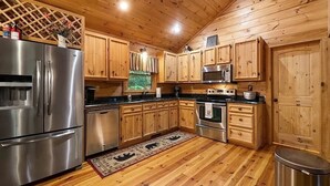 A kitchen with wooden cabinets, stainless steel appliances, and a wooden ceiling. - Peaceful and secluded with year-round mountain views and waterfall sounds. (Cherry Log)