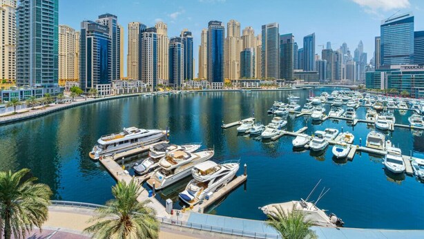 A marina with numerous boats docked, surrounded by high-rise buildings. - Modern 2BR with full Sea View | Pool & Gym (Dubai Marina)
