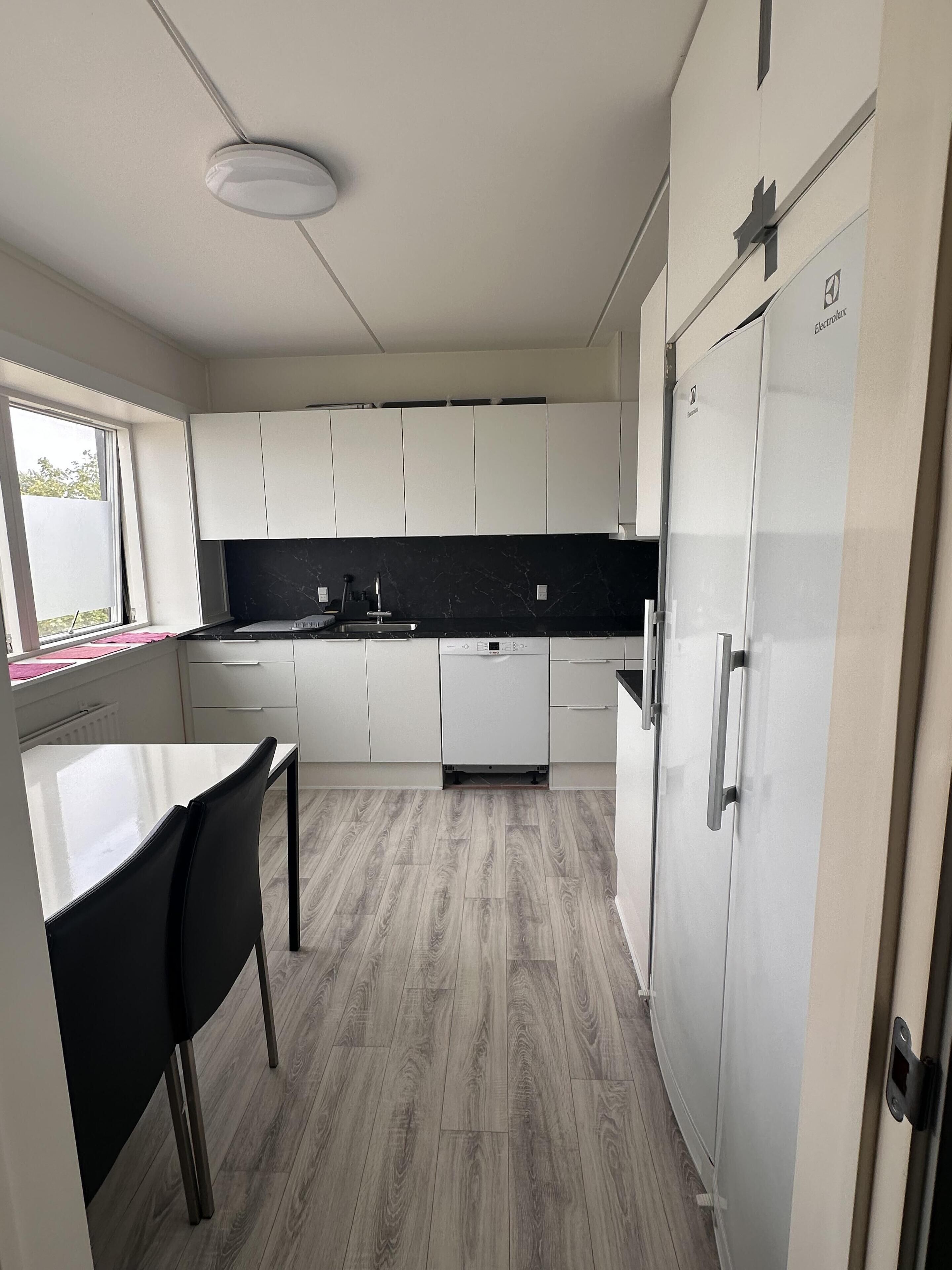 A modern kitchen with white cabinets, a black countertop, and a built-in dishwasher.