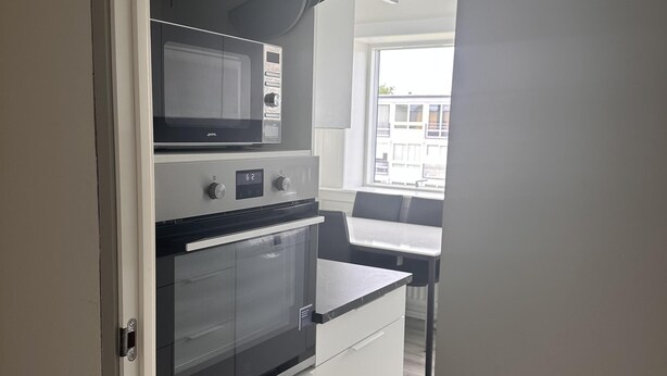 A compact kitchen with a built-in microwave, oven, and a small countertop. - Cozy Viby Apartment Near Kjaerlsund (Aarhus)