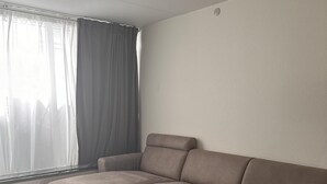 A modern living room with a sectional sofa, a glass coffee table, and a large window with curtains. - Cozy Viby Apartment Near Kjaerlsund (Aarhus)