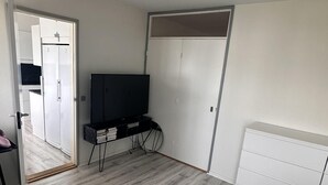 A bedroom with a bed, a TV, a wardrobe, and a door leading to another room. - Cozy Viby Apartment Near Kjaerlsund (Aarhus)