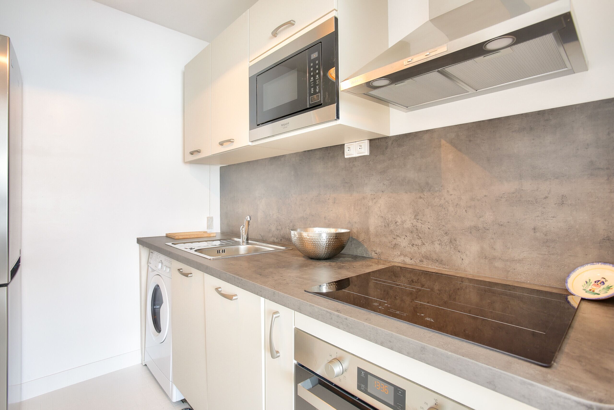 A modern kitchen with a built-in oven, microwave, and a stainless steel sink.