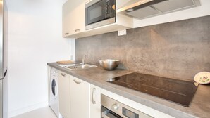 Una cocina moderna con microondas integrado, pileta de acero inoxidable y una cocina por inducción de gran tamaño.