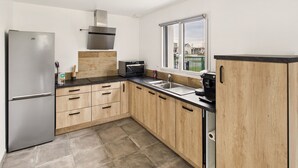 A modern kitchen with a stainless steel refrigerator, a built-in oven, and a coffee machine.