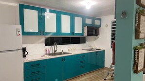 A kitchen with teal cabinets, a white countertop, and a stainless steel sink. - Mamita’s Beach House PR

 (Vega Baja)