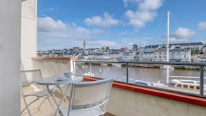 A balcony with a table and chairs overlooking a harbor with boats and a bridge. - On the Quai de Pornic, Apartment for 4 (Pornic)