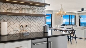 Eine moderne Küche mit Fischgrätmuster-Fliesen an der Spritzschutzwand, einem eingebauten Weinkühlschrank und einem Essbereich mit Meerblick.