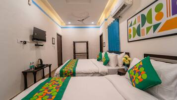 Habitación de hotel con dos camas, televisor, escritorio y ventilador de techo.