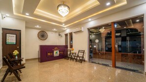A hotel reception area with a purple reception desk, a chandelier, and a glass door entrance. - Treebo Blu Vvu (Jodhpur)