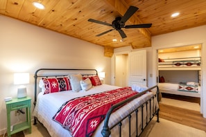 A bedroom with a bed, a ceiling fan, a nightstand, and a bunk bed in the adjacent room. - Good Medicine (Boone)