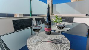 A table with two wine glasses and a bottle of wine on a glass table outdoors. - Apartment Marovic (Vir)