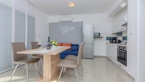 A modern kitchen with a dining area, including a wooden table, chairs, and a sofa. - Apartment Marovic (Vir)