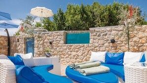 A stone wall with a pool, blue outdoor furniture, and umbrellas. - Villa Melary with the Pool, Jacuzzi & Ps5 surrounded with nature. (Kras)