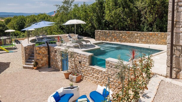 A pool area with stone walls, lounge chairs, and umbrellas. - Villa Melary with the Pool, Jacuzzi & Ps5 surrounded with nature. (Kras)