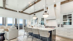 A spacious kitchen with a large island, bar stools, and a view of the ocean.