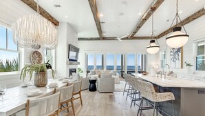 A spacious kitchen with a large island, modern pendant lights, and a view of the ocean.