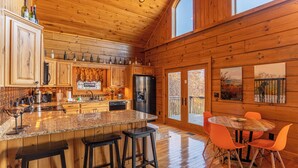 L’intérieur d’une cabane en bois comprend une cuisine, un coin repas et des tabourets de bar.