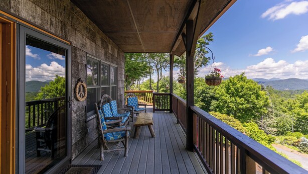 A wooden deck with outdoor seating, a view of mountains, and a hanging flower basket. - Chipmunk View Lodge (Blowing Rock)