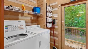 A laundry area with a washing machine, a drying rack, and a window with a view of greenery. - Pretty Spectacular (Banner Elk)
