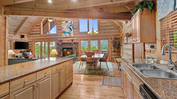 A spacious kitchen with wooden cabinets, a granite countertop, a fireplace, and large windows offering views of the outdoors. - Pretty Spectacular (Banner Elk)