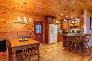 Un intérieur en bois comprenant une table à manger, des chaises, un réfrigérateur et un coin cuisine avec des placards et un évier.