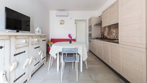 A compact kitchen with a dining area, a TV on a cabinet, and a small table with chairs. - 4002 Villetta Playa del Sol by Barbarhouse (Manduria)