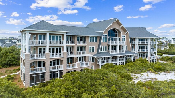 A multi-story residential building with balconies, large windows, and a prominent arched entrance. - Dune Trails | Beach Access | Shared Pool (Watersound)