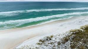A beach with clear blue water, a sandy shore, and a few people in the distance. - Dune Trails | Beach Access | Shared Pool (Watersound)