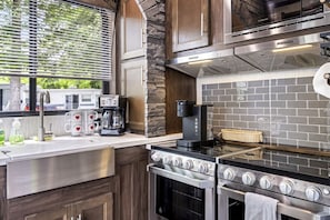 A modern kitchen with a stone accent wall, a built-in stove, and a coffee maker.
