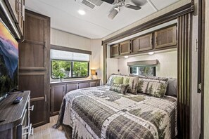 Une chambre à coucher avec un lit, un bureau et une fenêtre donnant sur un paysage verdoyant.