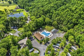 Vue aérienne d’un terrain de camping avec une piscine, un espace de stationnement pour les véhicules de loisirs et, au loin, un parcours de golf.
