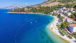 Une ville côtière dotée d’une plage, d’une eau d’un bleu limpide et de bâtiments qui bordent le rivage.