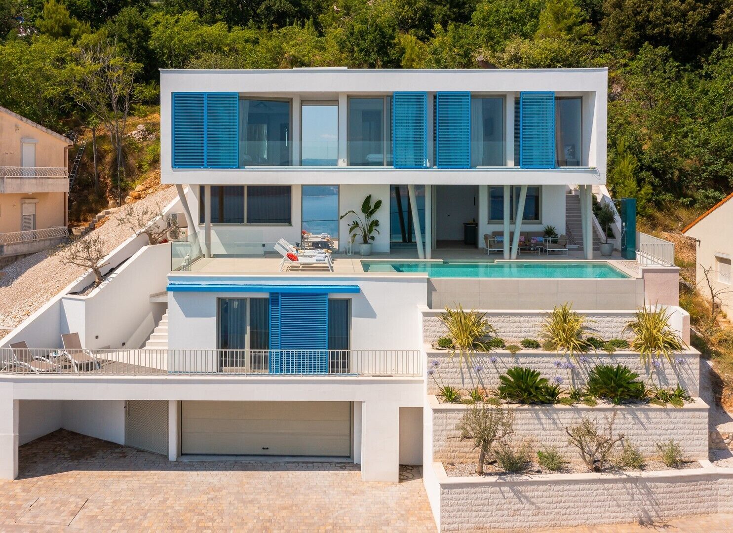 Une maison moderne à deux étages, dotée d’une piscine, d’un patio couvert et d’un garage.