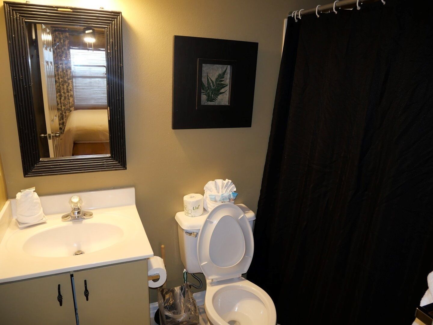 A bathroom with a sink, toilet, and a large mirror.
