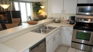 A modern kitchen with stainless steel appliances, white cabinetry, and a tiled floor. - Pelican Beach 1508 1 Bedroom Home (Destin)