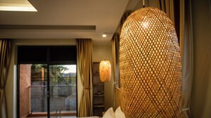 A hotel room with a bed, a large woven lamp, and a view through a glass door. - Akiiro Homes (Kampala)
