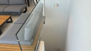A modern staircase with a wooden finish, a grey sofa with a cushion, and a glass railing. - Casa Isa, Idéalement Située Dans la Vielle Ville, Offre une Incroyable vue mer (Albufeira)