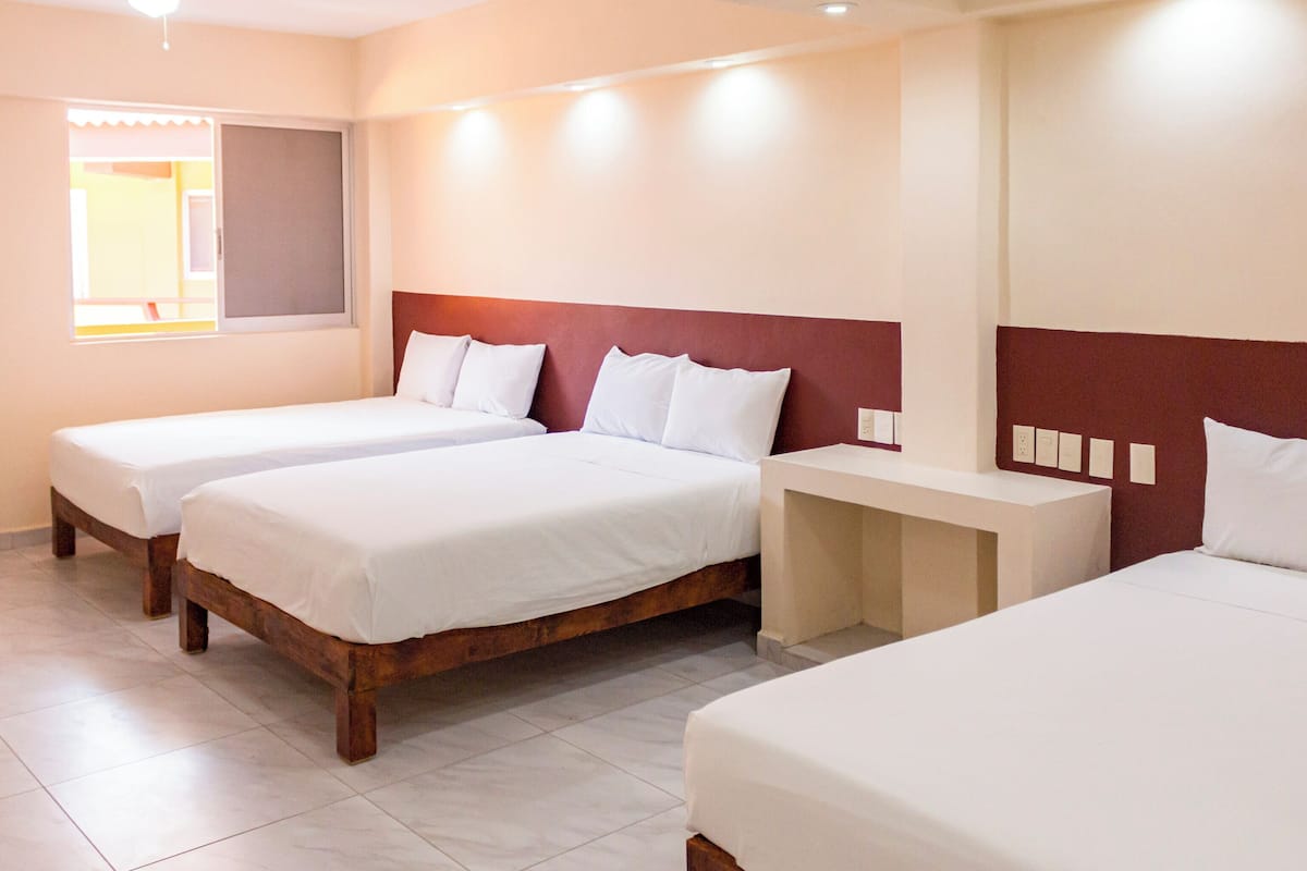 A hotel room with two single beds, a small bedside table, and a window with a view.