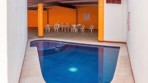 A swimming pool with a curved edge, surrounded by a tiled floor and walls.