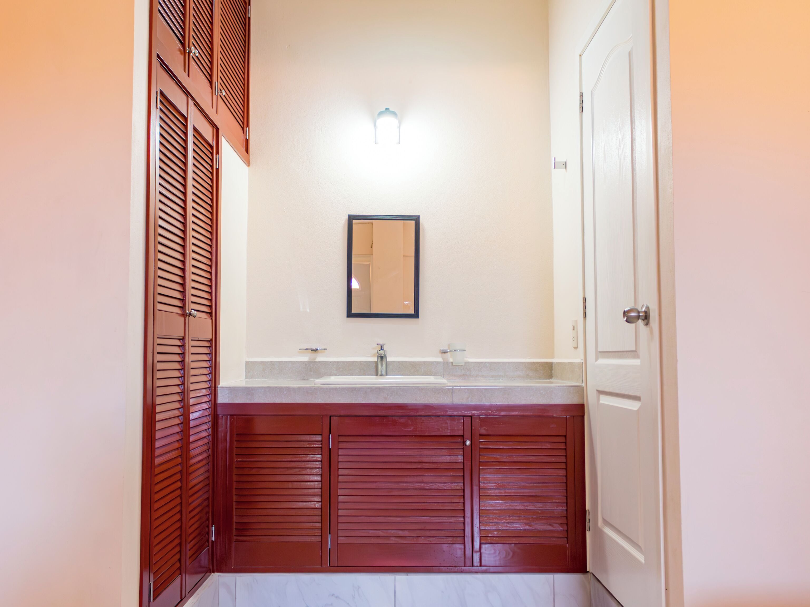 A bathroom with a double sink, a mirror, and wooden cabinets.