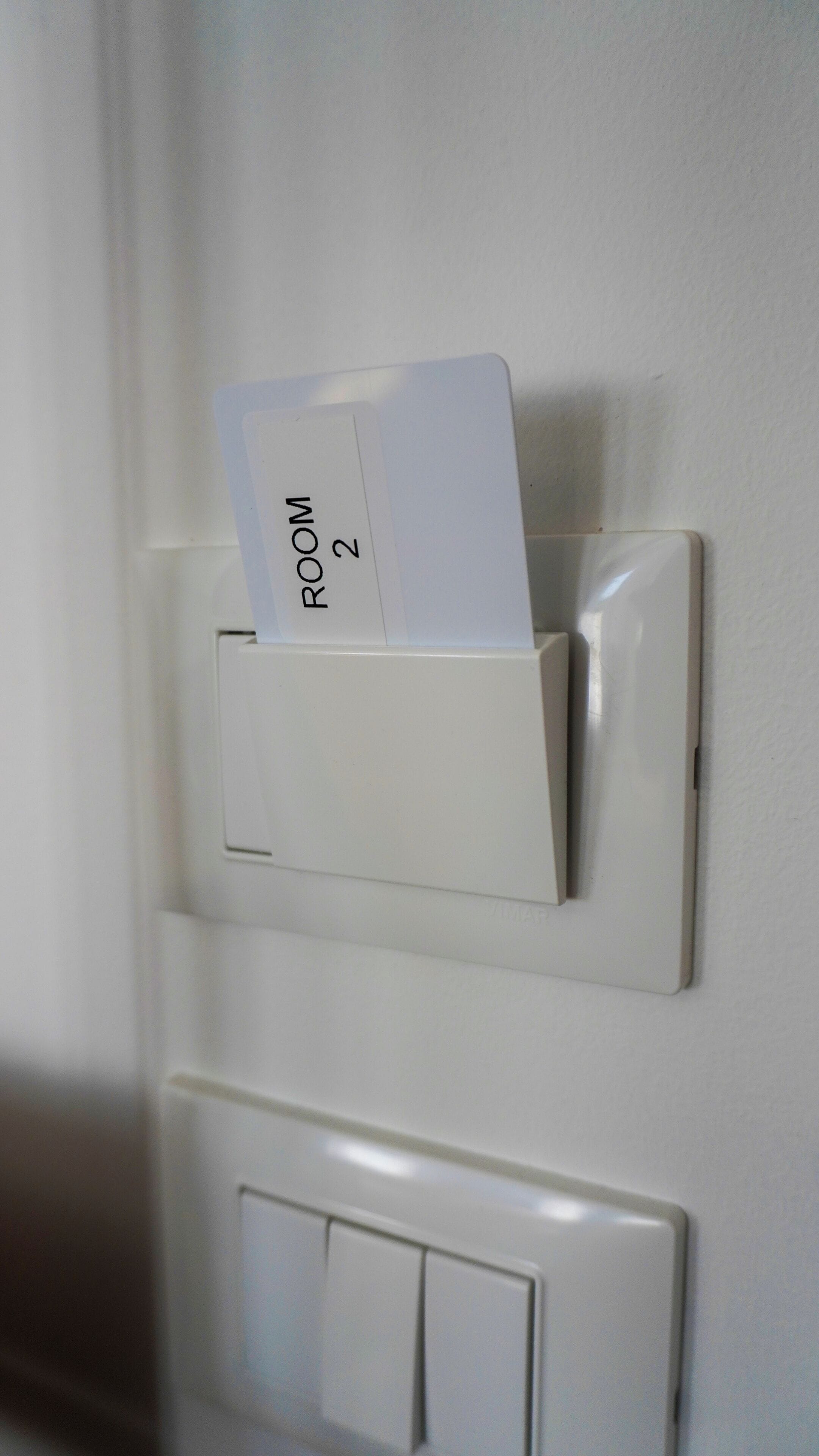 A white wall with a mail slot and a light switch.