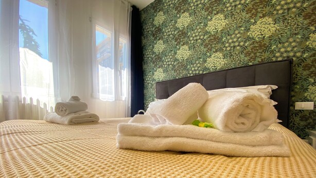 A hotel room with a bed, neatly folded towels, and a patterned wall. - The Platform Rooms (Ferrara)