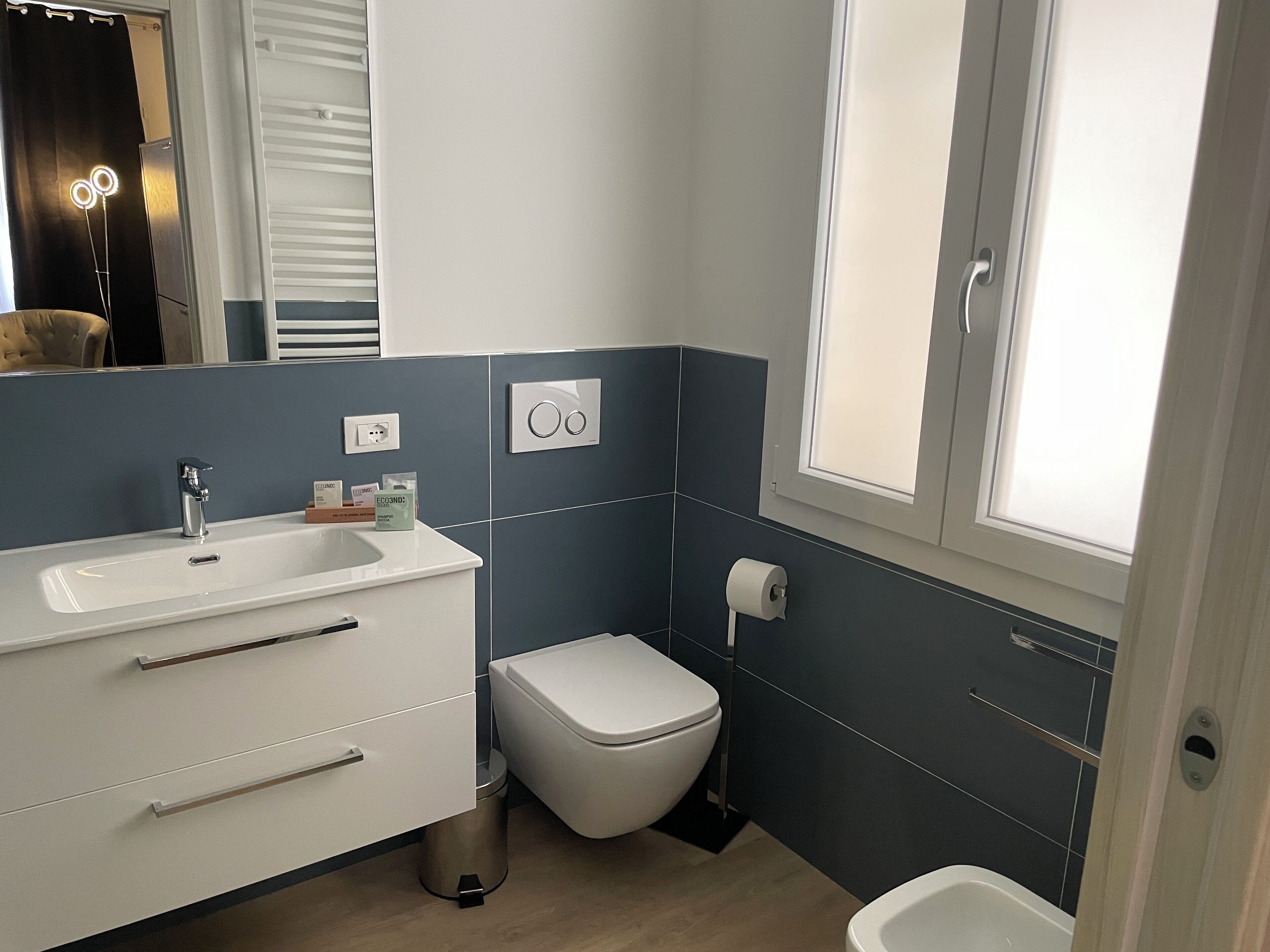 A modern bathroom with a white sink, vanity, and toilet.