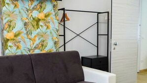 A modern living room with a sofa, a round coffee table, a TV mounted on the wall, and a door leading to another room. - The Platform Rooms (Ferrara)