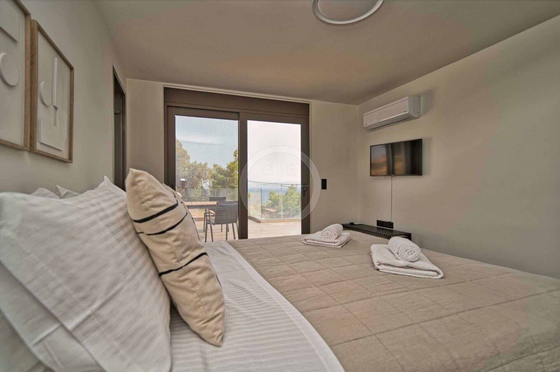 Ein Schlafzimmer mit Bett, Fernseher und Balkon mit Blick.