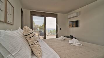 Ein Schlafzimmer mit Bett, Fernseher und Balkon mit Blick.
