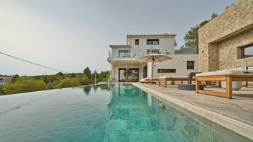 Eine moderne Villa mit privatem Infinity-Pool, Sitzgelegenheiten im Freien und einer Stein-Fassade.