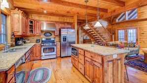 A spacious kitchen with wooden cabinets, stainless steel appliances, and a central island. - The Retreat (Banner Elk)
