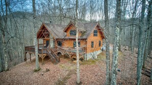 A wooden cabin with a deck, surrounded by trees. - The Retreat (Banner Elk)